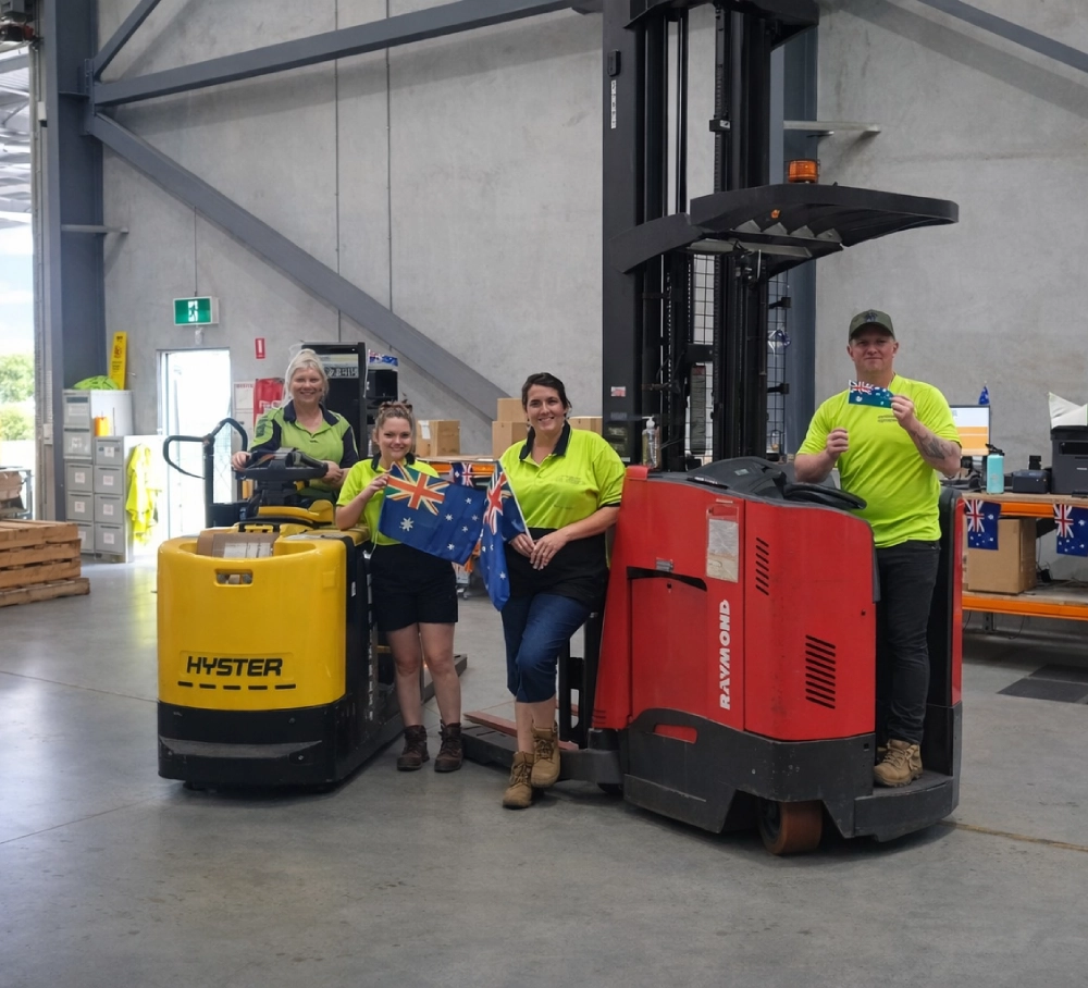 TLC Enterprise warehouse team standing with electric forklifts inside a distribution facility