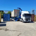 Truck loading a shipping container at a 3PL warehouse with container handling equipment and storage units
